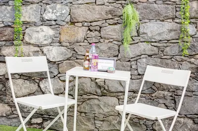 two chairs and a table with drinks on it next to a stone wall at Babosas Charm in Funchal