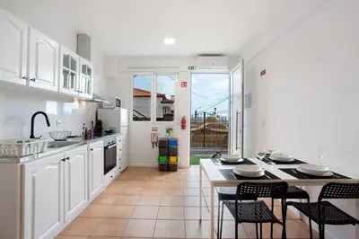 a kitchen with white cabinets and a table and chairs at Babosas Charm in Funchal