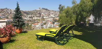 two lawn chairs and a christmas tree on a hill at Casa da Quinta in Funchal