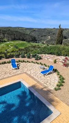 a swimming pool with two blue chairs next to it at Stunning Villa with Pool & View near beach in Budens