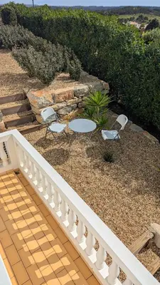 a patio with two chairs and a table and a stone wall at Stunning Villa with Pool & View near beach in Budens