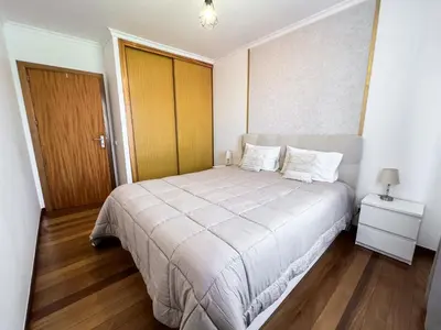 a bedroom with a large bed and a wooden door at The Pink Villa - Holidays in Madeira Island in Caniço
