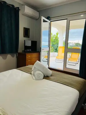 a bedroom with a bed and a balcony with chairs at Noite´s House - Prazeres in Prazeres