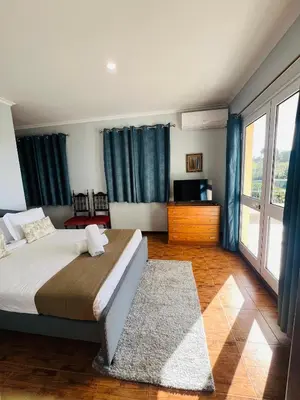 a bedroom with a large bed with blue curtains at Noite´s House - Prazeres in Prazeres