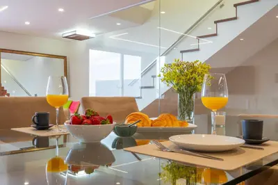 a table with a bowl of fruit and two glasses of orange juice at Tiz house in Funchal