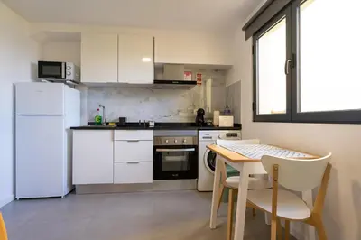 a kitchen with a white refrigerator and a table with chairs at Sun Hill Apartment in Santa Cruz