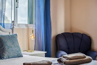 a bedroom with a bed and a chair and a window at De Freitas Home by Rent-a-key in Porto Moniz
