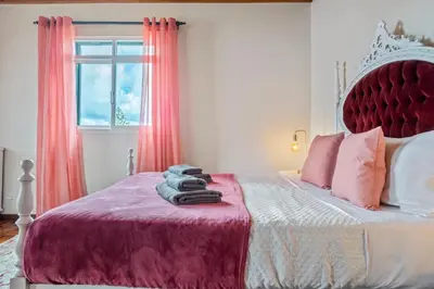 a bedroom with a bed with a red headboard and a window at De Freitas Home by Rent-a-key in Porto Moniz