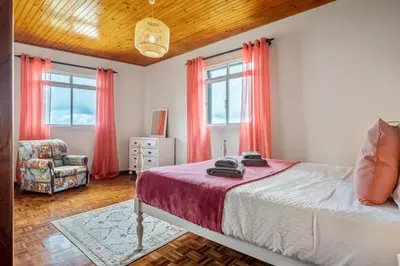 a bedroom with a bed and a chair and windows at De Freitas Home by Rent-a-key in Porto Moniz
