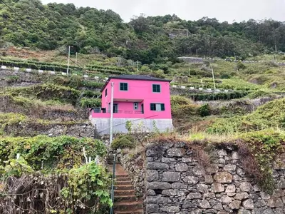 a pink house on the side of a hill at De Freitas Home by Rent-a-key in Porto Moniz