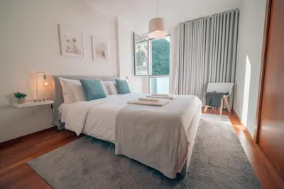a white bedroom with a large bed with blue pillows at Kora Home in Santa Cruz