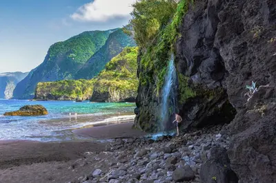 a waterfall on a beach with a person standing next to it at Rita's house in Ponta Delgada