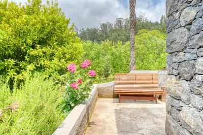 a wooden bench sitting next to a stone wall at Chalet da Nogueira, a Home in Madeira in Ponta do Sol