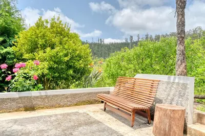 a wooden bench sitting next to a wall with flowers at Chalet da Nogueira, a Home in Madeira in Ponta do Sol