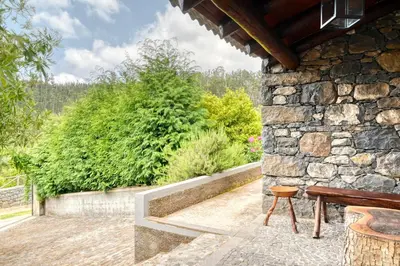 a patio with a bench and a stone wall at Chalet da Nogueira, a Home in Madeira in Ponta do Sol