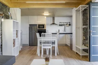 a kitchen with white cabinets and a table and chairs at Mountain Retreat by Homie in Porto Moniz