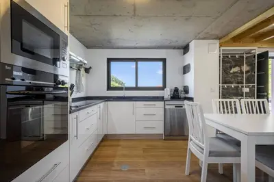 a kitchen with white cabinets and a table and a window at Mountain Retreat by Homie in Porto Moniz