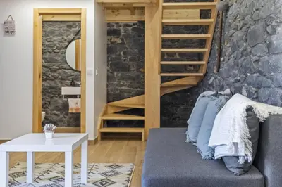 a living room with a couch and a stone wall at Mountain Retreat by Homie in Porto Moniz