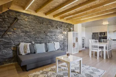 a living room with a couch and a stone wall at Mountain Retreat by Homie in Porto Moniz