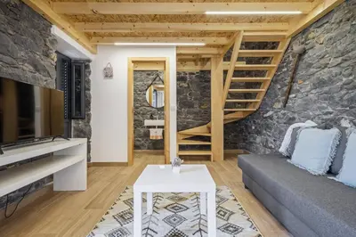 a living room with a stone wall and a staircase at Mountain Retreat by Homie in Porto Moniz