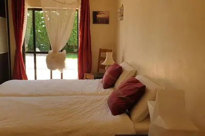 a bedroom with two beds with red pillows and a window at Casa KIWI 3 chambres et piscine in Luz