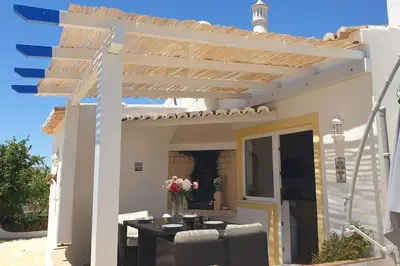 a patio with a pergola with a table and chairs at Casa KIWI 3 chambres et piscine in Luz