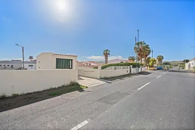 an empty street with a white fence and palm trees at Casa Yucca - Porto Santo Island in Porto Santo