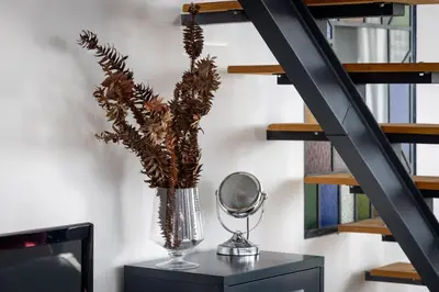 a vase with flowers on a table next to a staircase at Panoramic House in Ribeira Brava