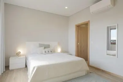 a white bedroom with a large bed and a window at Casa das Raposinhas I in Funchal