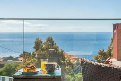 a table with a plate of food and a cup of orange juice at Casa das Raposinhas I in Funchal