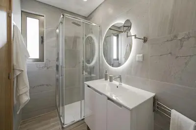 a white bathroom with a sink and a shower at Casa das Raposinhas I in Funchal