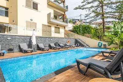 a swimming pool with chaise lounge chairs next to a building at Casa das Raposinhas I in Funchal