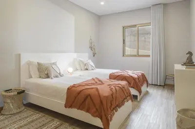 a white bedroom with two beds and a window at Casa das Raposinhas II in Funchal