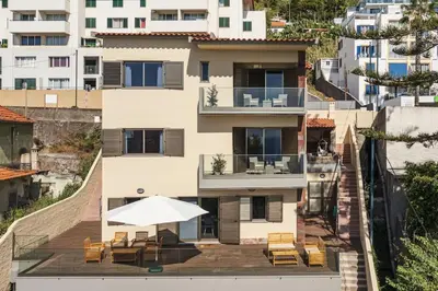 a building with a patio with an umbrella and chairs at Casa das Raposinhas II in Funchal