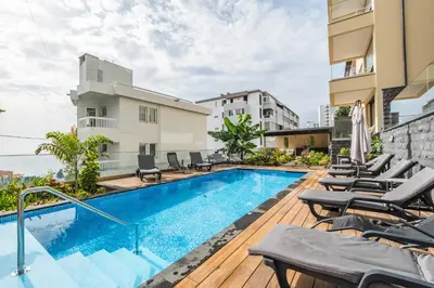 a swimming pool with chaise lounge chairs next to a building at Casa das Raposinhas II in Funchal