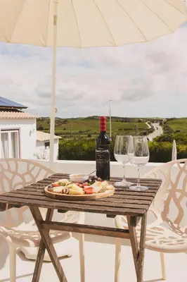a table with a bottle of wine and two glasses at Pure Flor de Esteva in Vila do Bispo