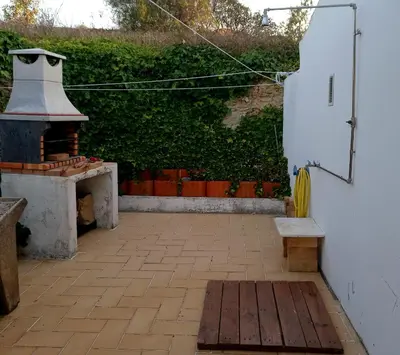 a patio with a fireplace and a bench and bushes at Charme Rústico in Aljezur