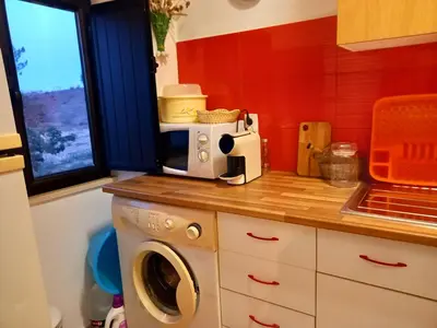 a kitchen with a washing machine and a microwave at Charme Rústico in Aljezur