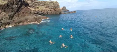 four people swimming in the ocean near a cliff at Reis Magos Beach Caniço Sea line Apartment in Caniço