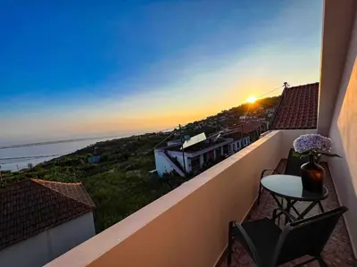 a balcony with a table and chairs and the sunset at Apartment 1BR Hills over Ponta do Sol, sea view in Ponta do Sol