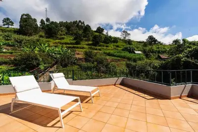 a patio with two white chairs and a balcony at Apartment 1BR Hills over Ponta do Sol, sea view in Ponta do Sol