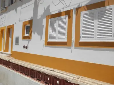 a building with white and brown shuttered windows at Casa Baptista in Vila do Bispo