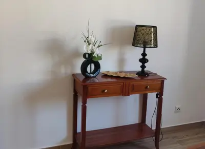 a table with a lamp and a vase of flowers on it at Casa Baptista in Vila do Bispo