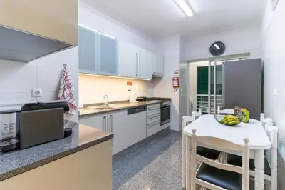 a kitchen with white cabinets and a white table at Ocean View Flat in Câmara de Lobos
