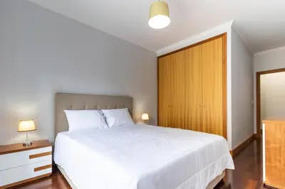 a bedroom with a white bed and a wooden door at Ocean View Flat in Câmara de Lobos