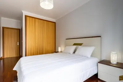 a bedroom with a large white bed and wooden cabinets at Ocean View Flat in Câmara de Lobos