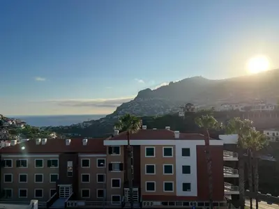 a view of a building with a mountain in the background at Ocean View Flat in Câmara de Lobos