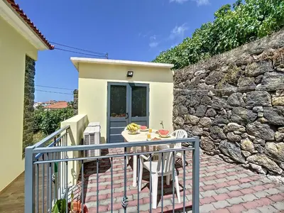 a patio with a table and chairs and a stone wall at My School I by Atlantic Holiday in Ponta Delgada
