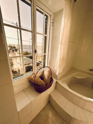a bathroom with a window and a basket next to a tub at Casa Carneirinho by Olá Madeira in Paul do Mar