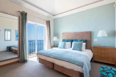 a bedroom with a large bed and a large window at Balancal Apartments and Villas Palheiro Village by Holiday Rental Madeira in Funchal